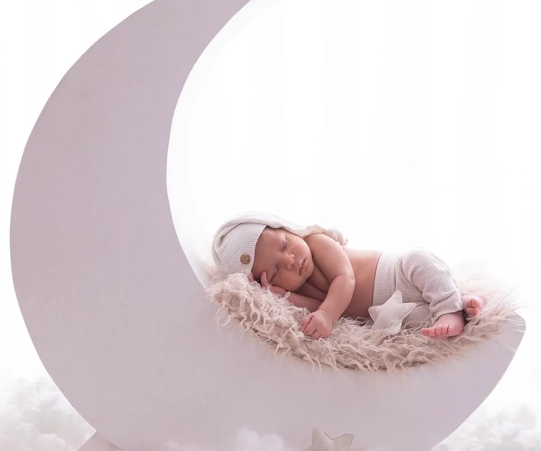 I love getting creative in my studio. Here, a sweet newborn dreams peacefully on a crescent moon prop, surrounded by soft clouds, creating a truly magical and whimsical portrait.