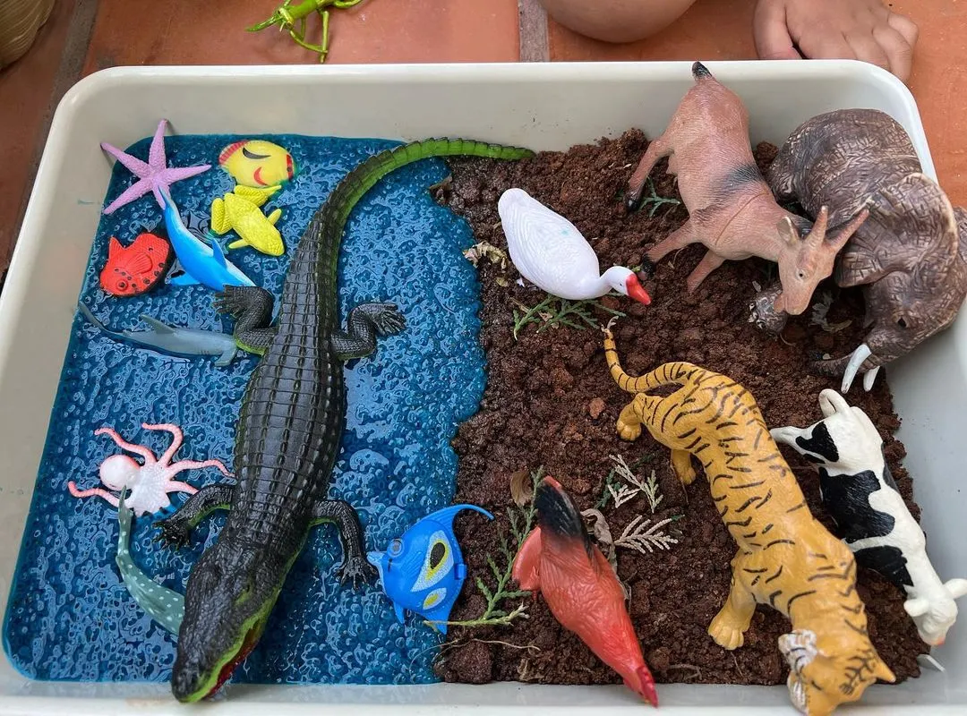 Before the fun begins, I set up inviting sensory trays like this one for sorting land and sea animals. This station uses taste-safe mud and blue-dyed chia seeds, creating a rich tactile world for kids to explore animal habitats.