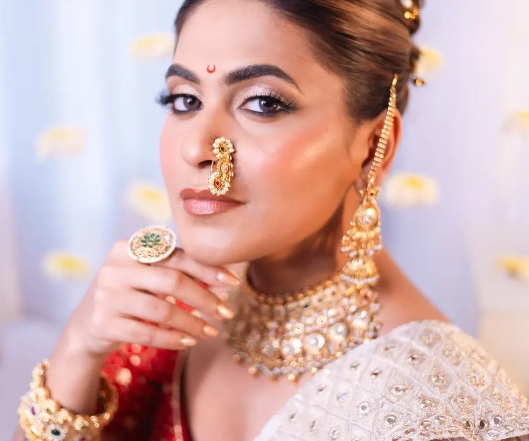 For this artistic photoshoot, we created a divine "Apsara" look. It features sharp, defined makeup with a bronzed glow, a traditional Marathi nath, and a classic bridal bun. This style is perfect for editorial shoots or for brides who want a truly royal and timeless look.