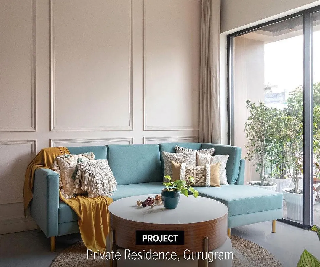 This living room in a private Gurugram residence balances comfort with quiet elegance. We used soft, neutral wainscoting and a calming color palette to create a timeless space, punctuated by a pop of color from the teal sofa for a modern, personalized feel.
