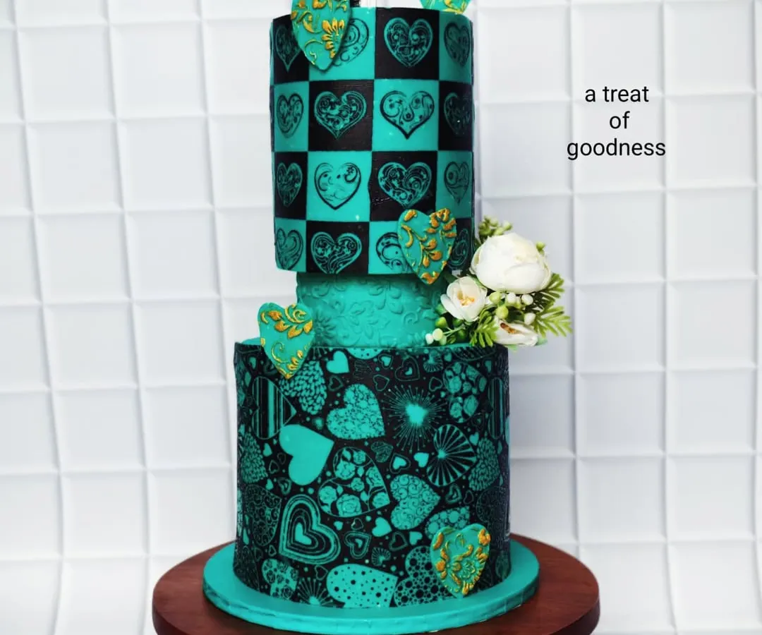 This two-tier wedding cake shows how artistic you can get without fondant. I used a detailed stenciling technique with black cocoa on teal buttercream to create the intricate heart patterns, giving it a bold, modern, and unforgettable look.