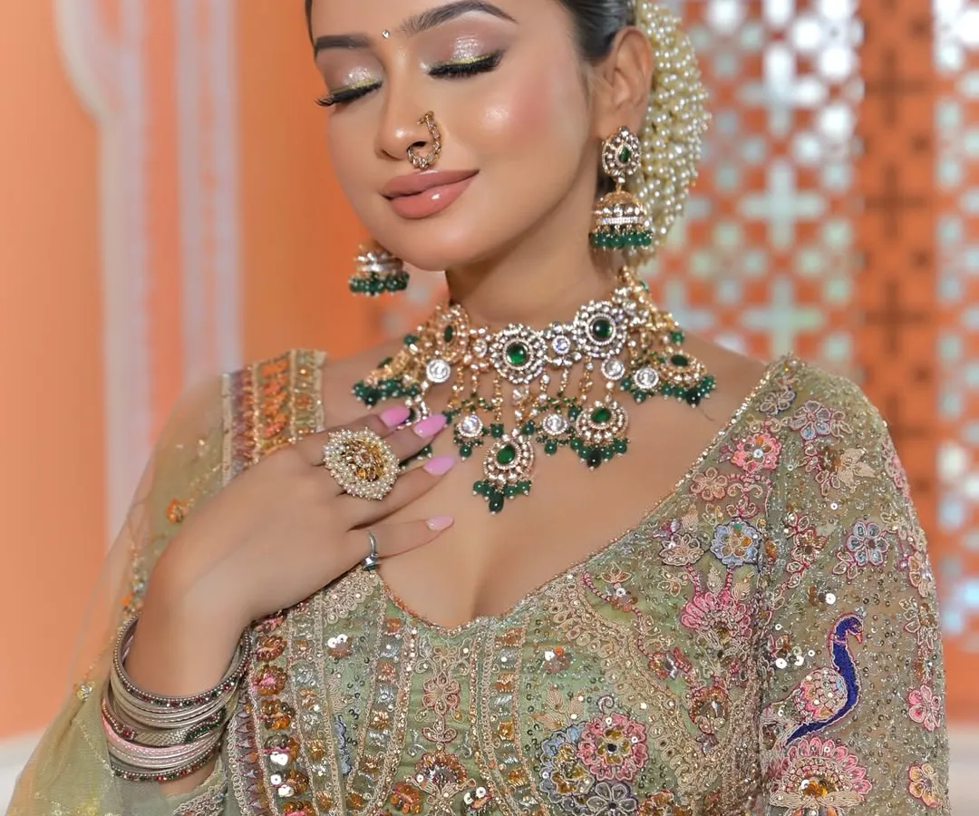 A perfect example of how jewellery can elevate a look. This stunning Polki and green gemstone choker set contrasts beautifully with the pastel green lehenga. This is a popular choice for brides who want a traditional feel with a touch of modern color.