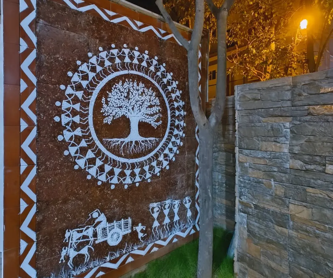 This is my Tree of Life Warli mural, painted on an exterior compound wall and seen here at night. The central tree symbolizes life and connection, surrounded by figures in a celebratory dance, creating a powerful piece of traditional Indian wall art.