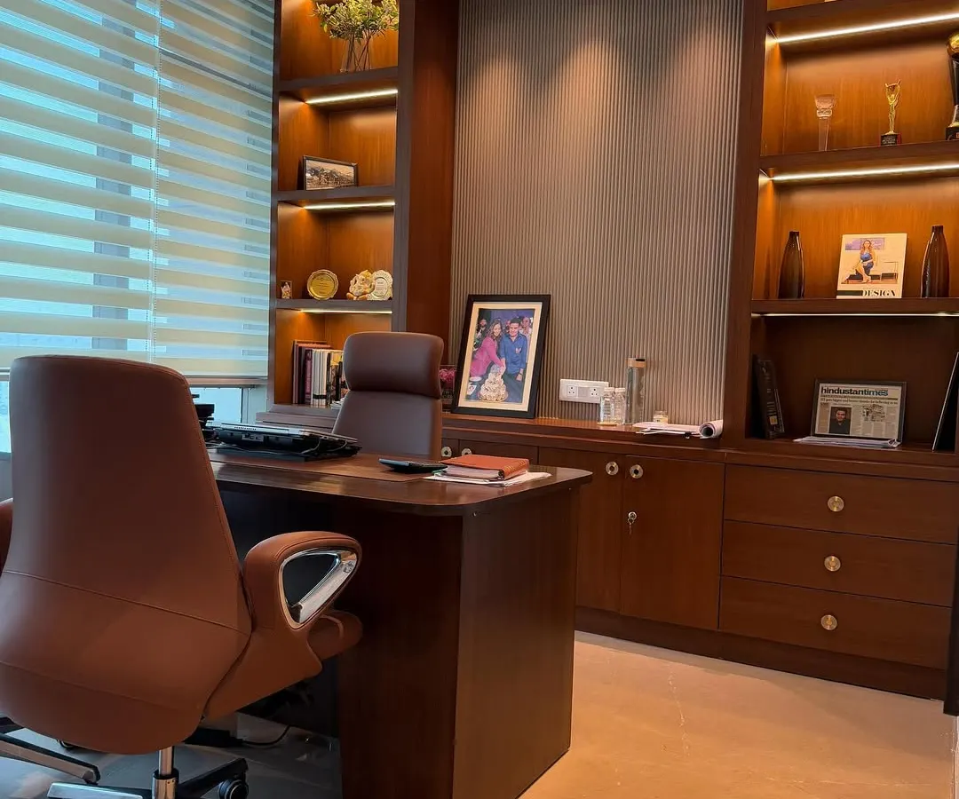 We designed this executive office to be both productive and aesthetically pleasing. The custom-built wooden shelving unit features integrated backlighting to highlight awards and decor, while the ergonomic leather chair and spacious desk provide ultimate comfort. The combination of rich wood tones and soft, layered lighting creates a powerful yet sophisticated workspace.