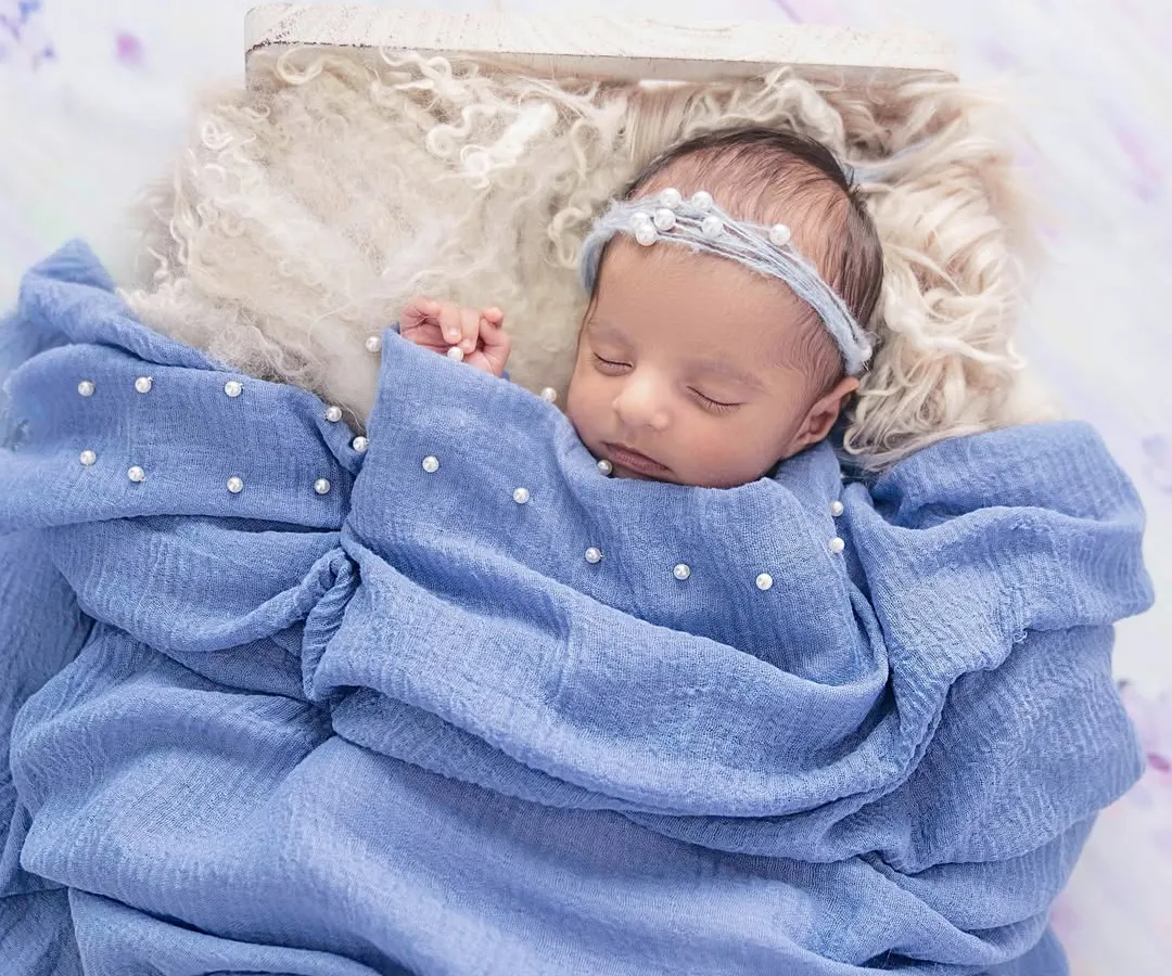 The purest serenity. I specialize in creating a safe and peaceful environment to capture your newborn in their most natural state. This little one, swaddled in soft blue and adorned with delicate pearls, is a perfect example of the timeless, artful portraits I create.