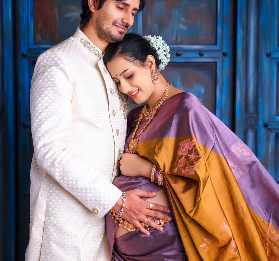 The bond between partners shines through in this elegant traditional maternity portrait. Dressed in a beautiful silk saree, the couple shares a quiet, loving moment, showcasing a timeless connection.