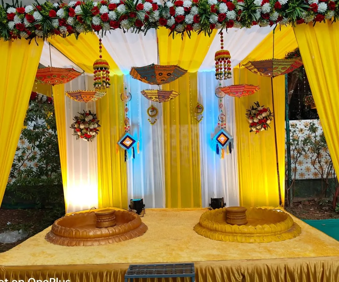 For a Haldi ceremony, it's all about bright, happy colors. This setup features a traditional yellow drape backdrop, decorative Rajasthani umbrellas, and low seating (baithak) for the rituals, making it perfect for photos and creating a festive vibe.