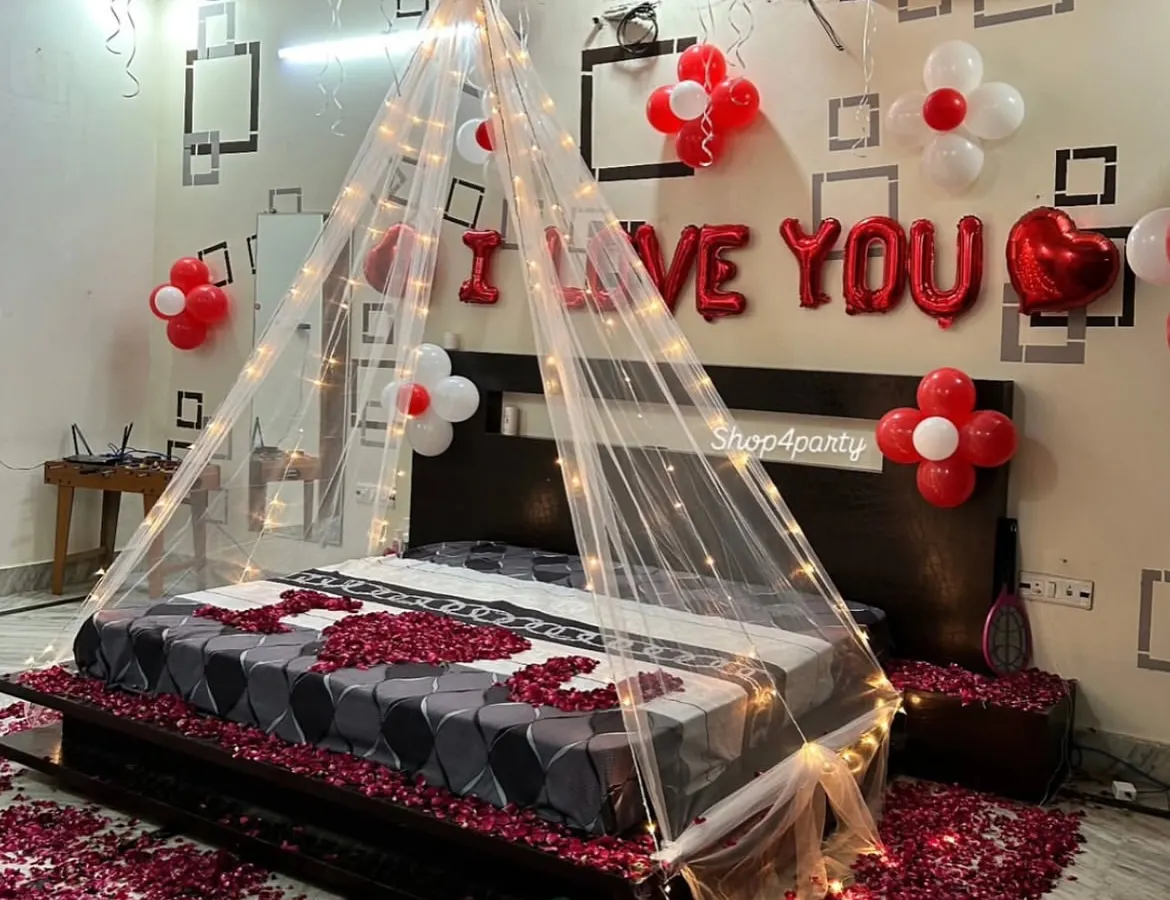 For a truly romantic gesture, we transformed this bedroom with a fairy light canopy, hundreds of red and white balloons, and a floor covered in rose petals. The "I LOVE YOU" balloon letters add a perfect finishing touch to this anniversary or birthday surprise.