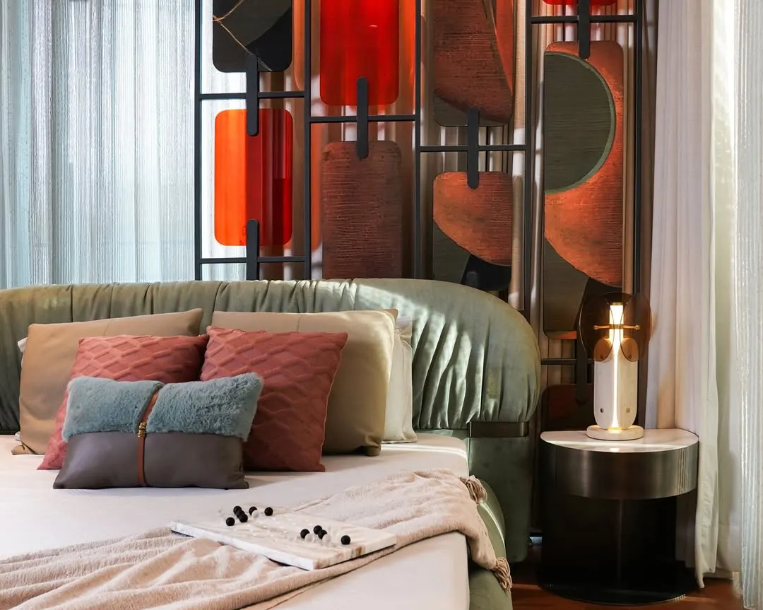 A close-up of the master bedroom at Matoshri Residence, showcasing our attention to detail. The design features a sage-green upholstered bed, a custom sculptural headboard with leather and veneer panels, and brass accents, creating a sanctuary of comfort and character.