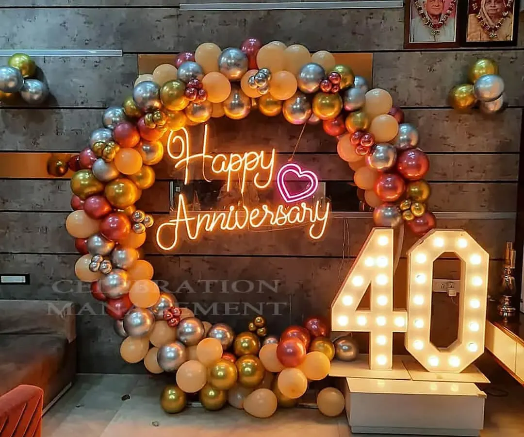 Celebrating a 40th anniversary with an elegant balloon ring in metallic tones, a custom "Happy Anniversary" neon sign, and large marquee numbers.