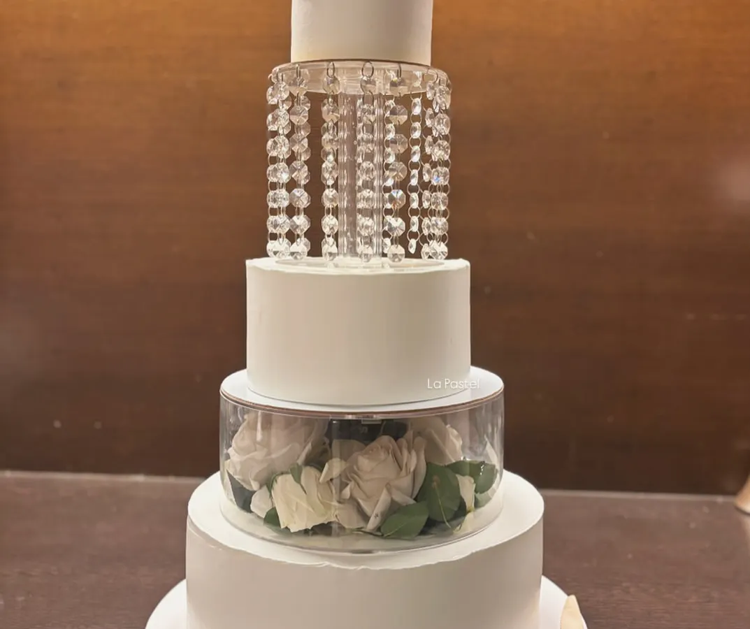 For a touch of pure luxury, this four-tier eggless wedding cake is an absolute showstopper. It features a tier of cascading crystals that sparkle like a chandelier, and another filled with fresh white roses, creating a truly glamorous look.
