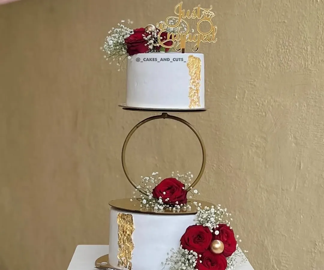 We love being part of new beginnings. This two-tier engagement cake features a delicate gold hoop separator and is adorned with fresh red roses and baby's breath. You can learn how to properly prep and place fresh florals on cakes for a food-safe and beautiful finish.