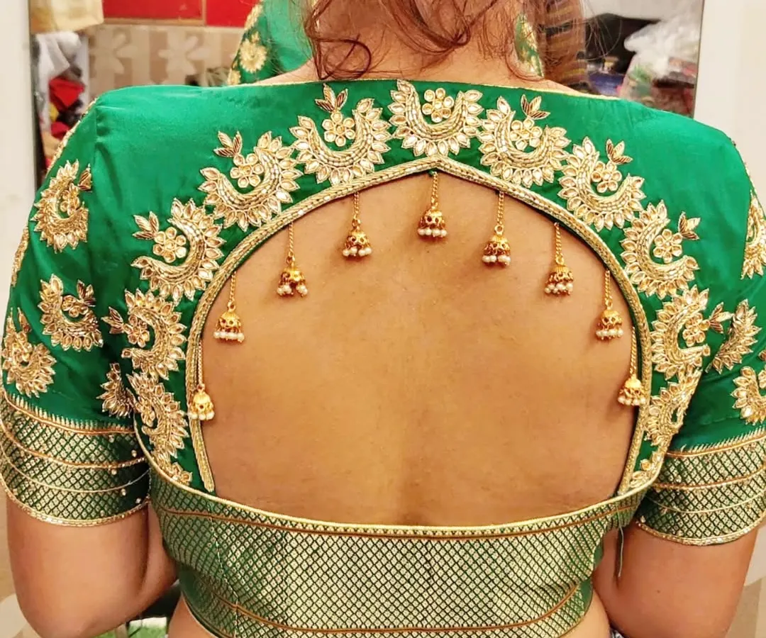 The beauty is in the details. This custom designer blouse features a dramatic arched keyhole back, framed with intricate gold zardosi embroidery and delicate hanging jhumkas. I work closely with clients to create unique back designs that make their ethnic wear truly one-of-a-kind.