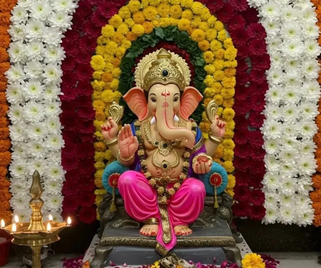 For Ganpati festival celebrations, I create stunning backdrops like this one. This mandap decoration features a dense arch made entirely of fresh flowers, including white chrysanthemums, yellow and orange marigolds, and red carnations, for a vibrant and traditional look.