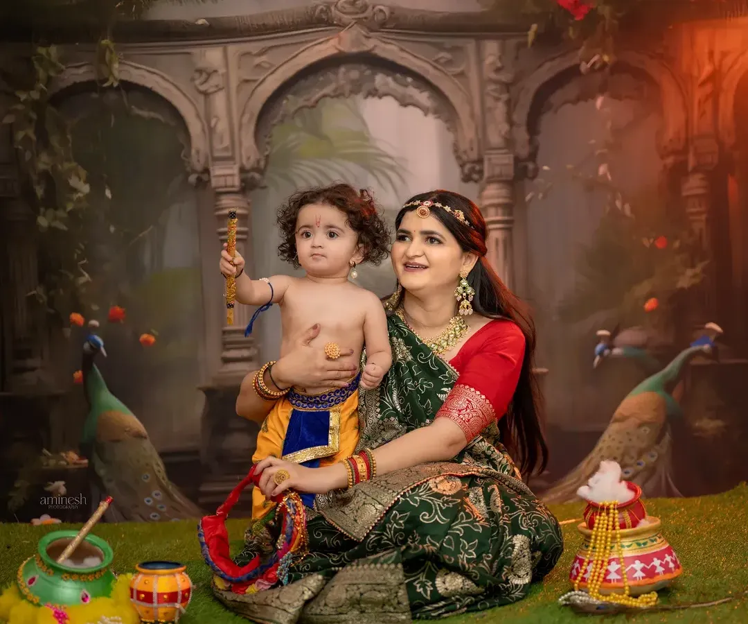 The bond between a mother and child is special, and my Janmashtami theme photoshoot brings it to life. Here, a mother dressed as Yashoda shares a moment with her baby Krishna, complete with a flute and a backdrop of Vrindavan.