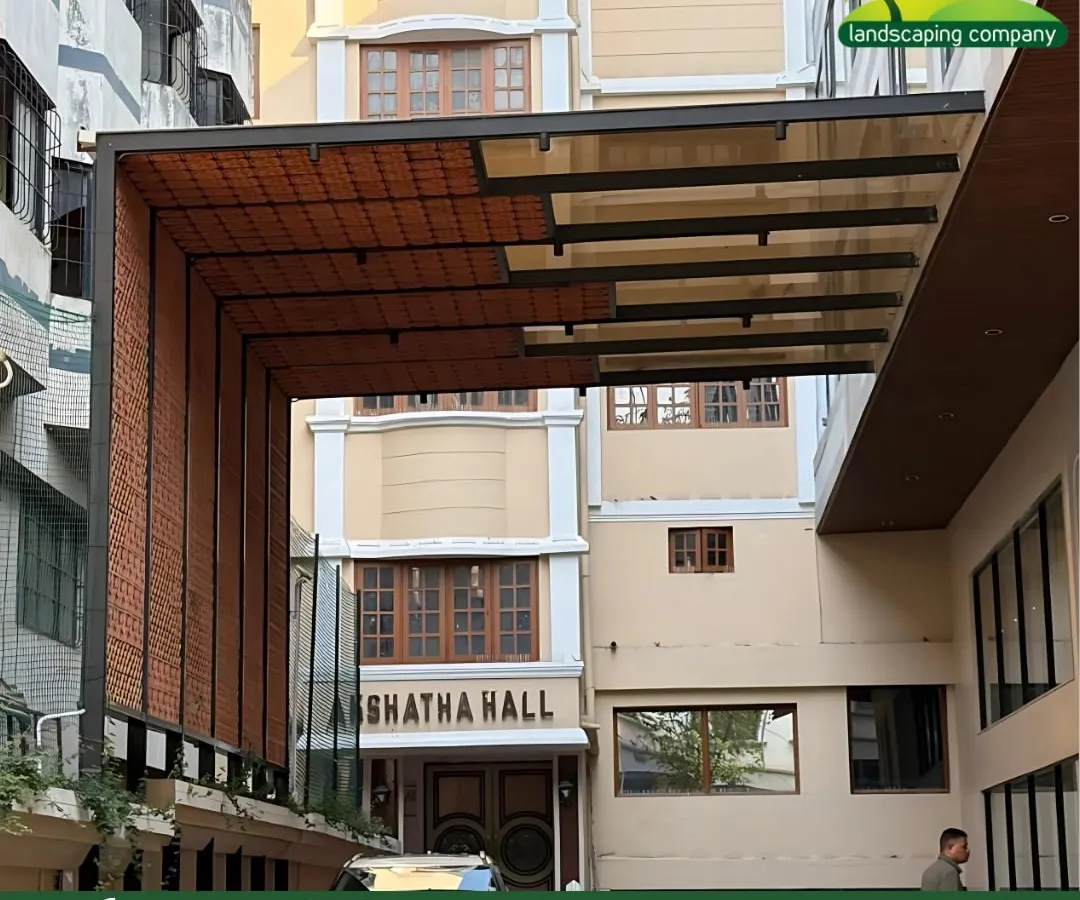 This modern pergola, installed at a commercial hall in Bangalore, demonstrates our skill in structural landscaping. The design features a tinted glass roof and clay tile cladding, providing a functional and stylish shaded entrance.