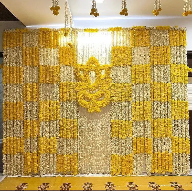 For a Haldi ceremony at home, I designed this full feature wall using a checkerboard pattern of yellow and white marigolds. The centerpiece is a Ganesha motif made entirely of fresh yellow marigold flowers, making it a perfect photo backdrop.