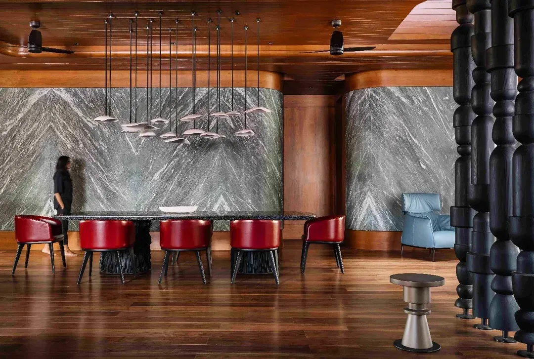 In this Bengaluru residence, the dining area becomes a canvas for material richness. We juxtaposed bold green marble against warm wood and vibrant red chairs, using custom pendant lighting to create a sense of depth and resonance between space and memory.