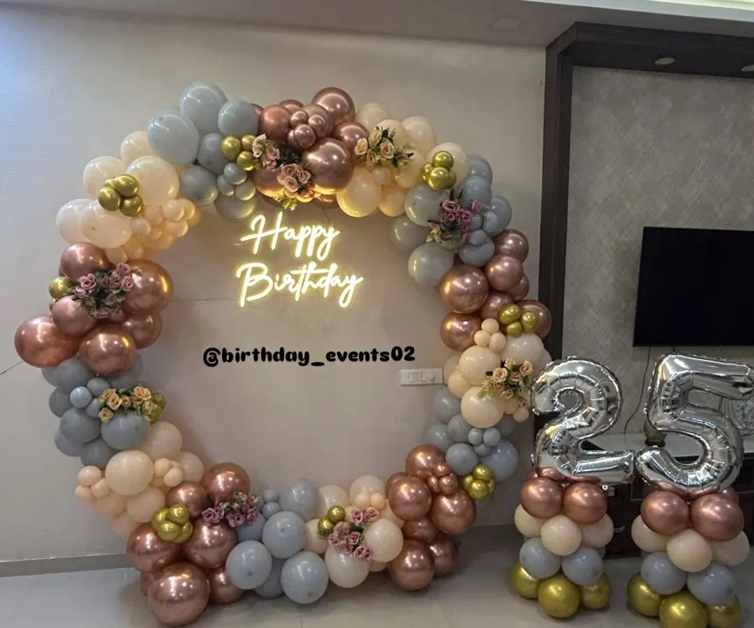 Our signature ring backdrops are a client favorite. This elegant setup features a full circle of pastel, rose gold, and grey balloons, a custom neon sign, and matching balloon stands for the birthday age, creating a polished and trendy photo corner.