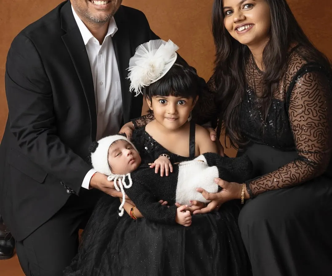 There is nothing more beautiful than a family coming together to celebrate a new life. This is a full family portrait, with everyone dressed in coordinated black outfits, creating a timeless and elegant memory.