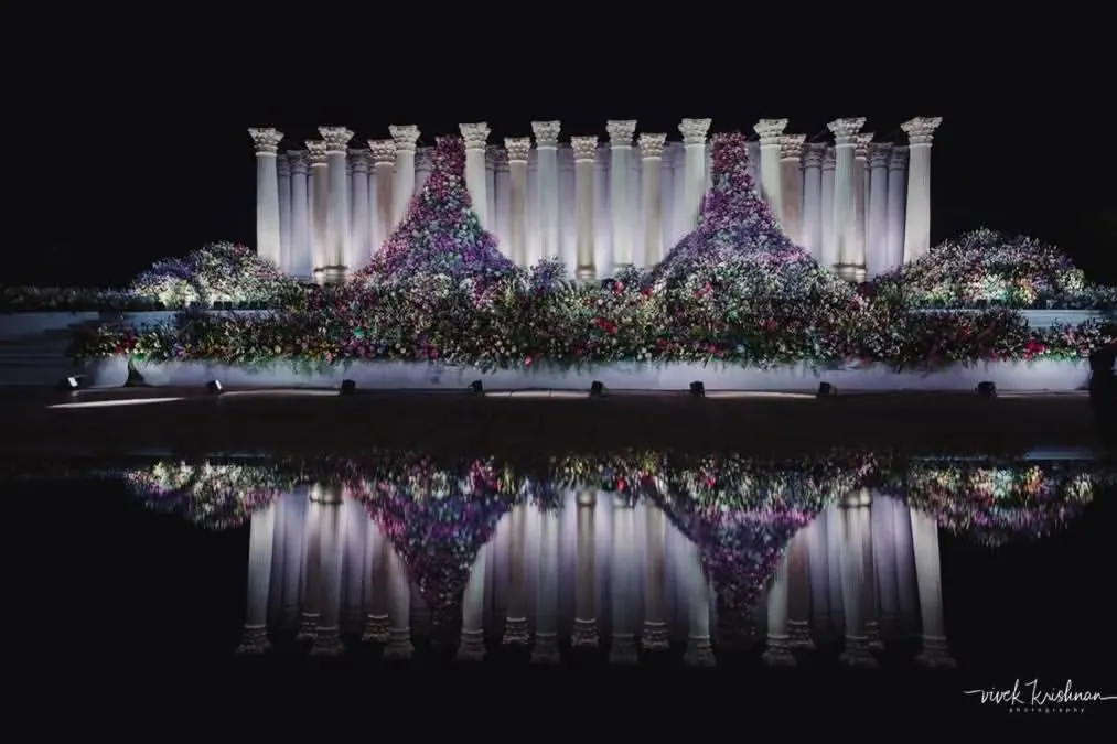 We don't just build structures; we create art. For this reception, we installed 22-foot Roman pillars and set them against a water body to create this stunning reflection. It's about achieving that unconventional balance between simple, grand, and dramatic.