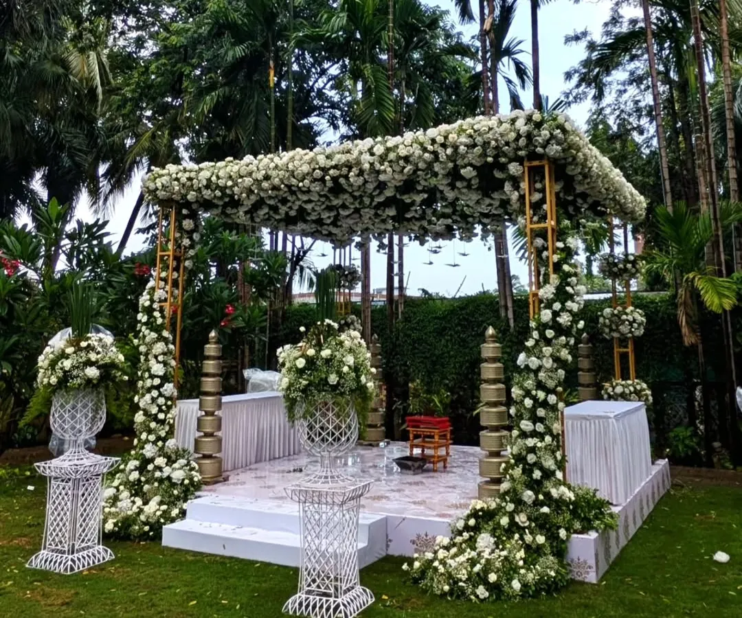 For this outdoor ceremony, I created a serene floral mandap using a canopy of white roses and lush greenery. The design blends seamlessly with the natural garden setting, crafting a tranquil and elegant space for the couple to exchange their vows.