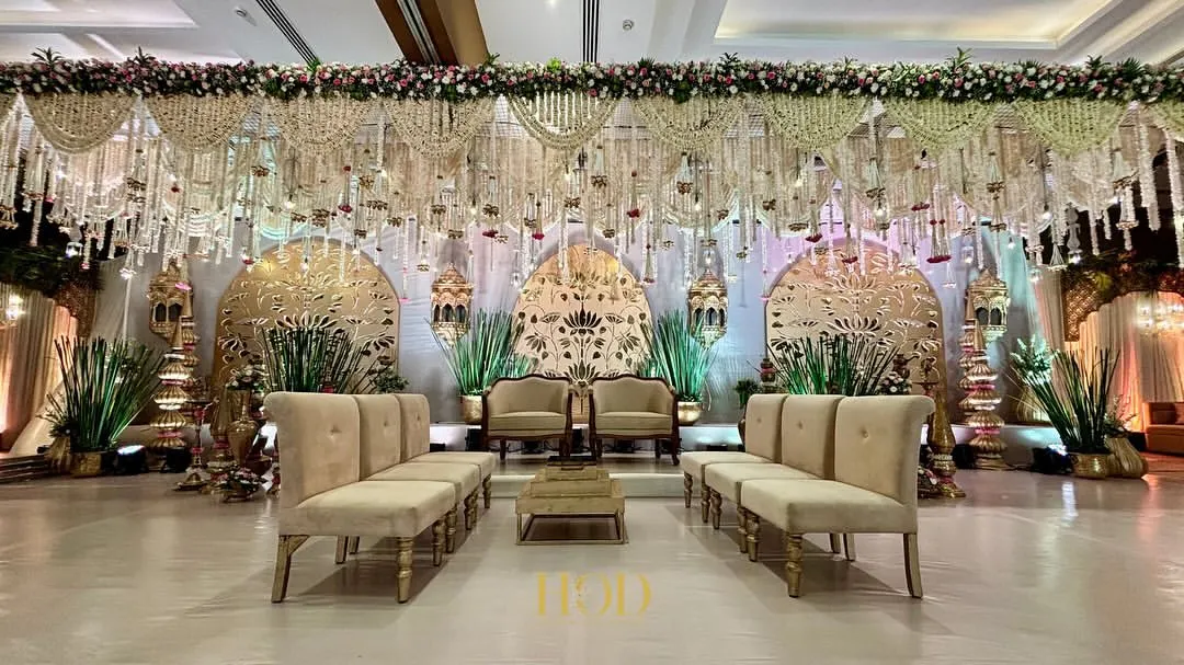 The stage is the heart of your celebration, and I make sure it's nothing short of spectacular. This expansive wedding reception stage features intricate golden laser-cut panels and cascading floral arrangements, creating a backdrop of pure opulence and grandeur.