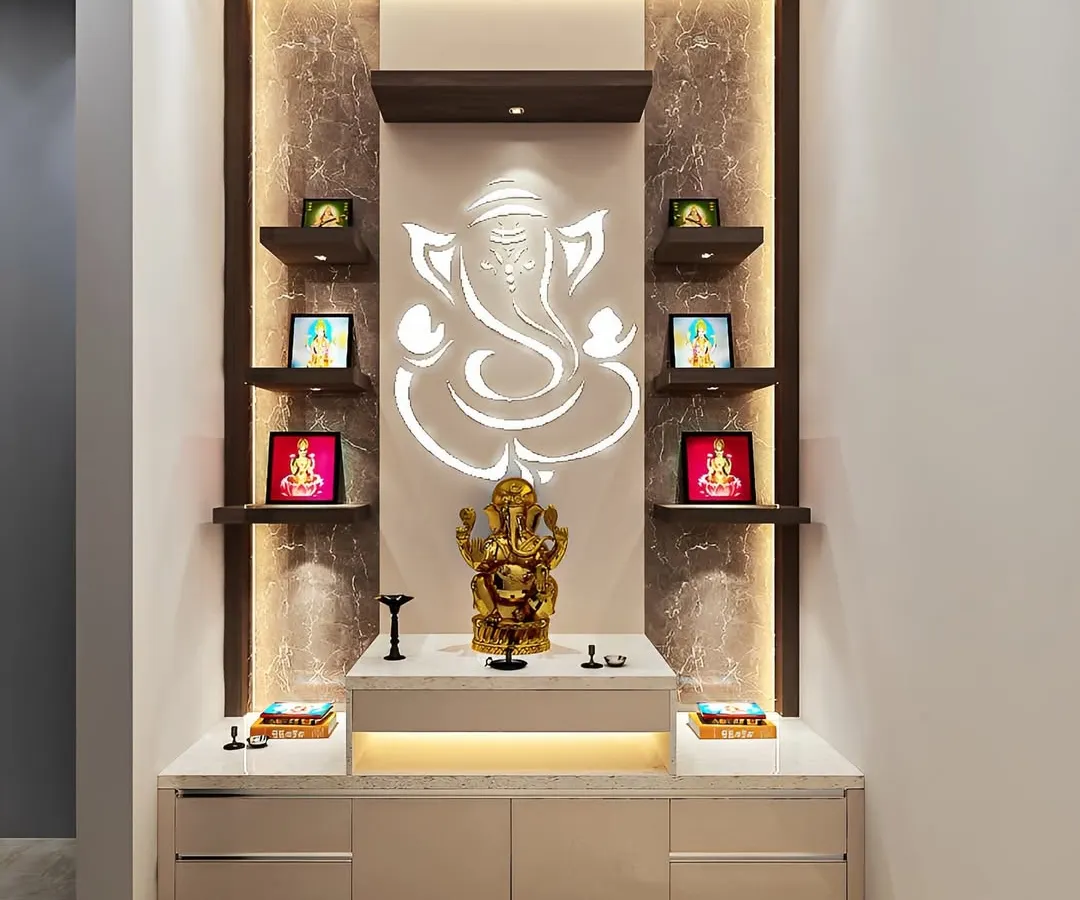 A perfect example of a contemporary pooja unit for a modern Bangalore apartment. This design features a stunning backlit Ganesha motif on a marble-finish panel, providing a soft, divine glow. Floating shelves offer space for smaller idols and frames, while the glossy base cabinet provides sleek, handleless storage for pooja essentials.