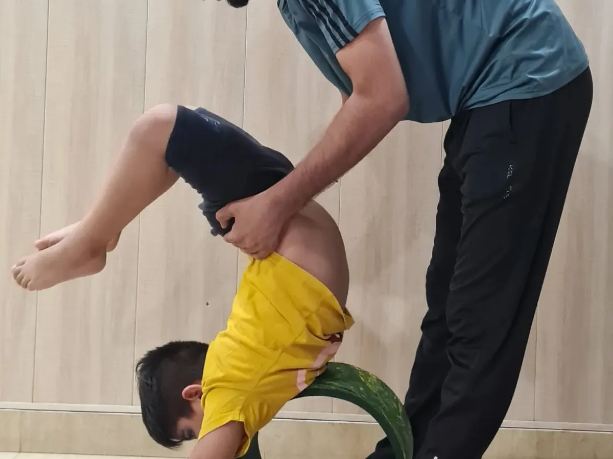 Safety and proper alignment are my top priorities in kids' yoga. Here, I am assisting one of our young yogis in a backbend using a yoga wheel, helping him build strength and flexibility in a controlled and supportive way.