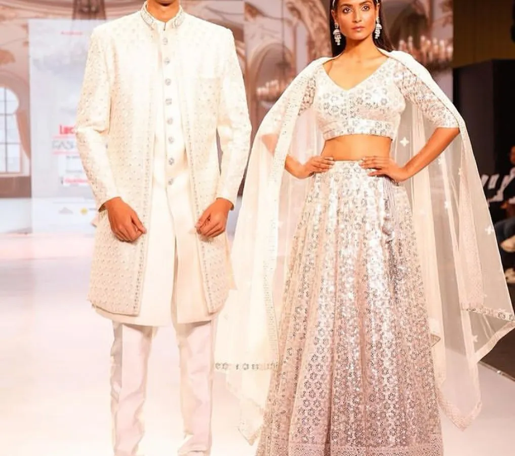 For the modern couple, this all white coordinated set is pure elegance. The bride's chic lehenga with a cape and the groom's textured white sherwani create a sophisticated look, perfect for a reception or engagement.