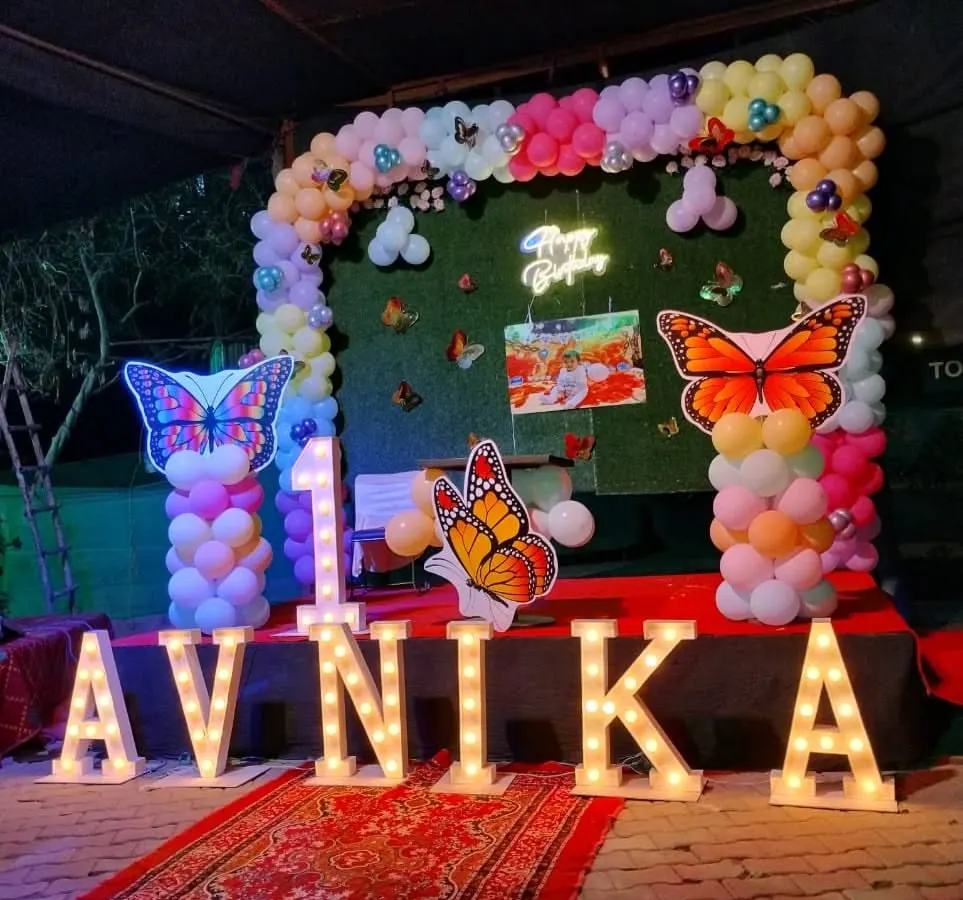 For a truly grand first birthday, I can bring any theme to life. This butterfly garden theme for Avnika's party included a lush balloon arch, a green backdrop, and large, lit-up marquee letters spelling her name, creating a magical photo opportunity.
