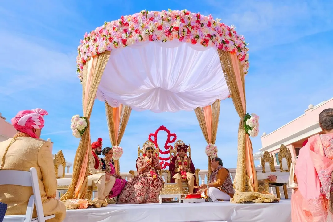 A beautiful daytime wedding ceremony under a stunning floral mandap. We capture the grandeur of your wedding setup and the sacred rituals, ensuring every detail of the ceremony is preserved against a bright, clear sky.