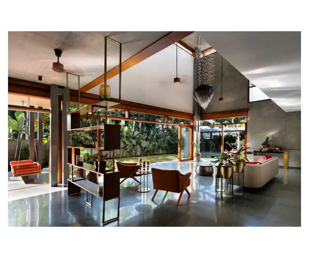 Inside the House of Canopies, a triple-height living area dissolves into the garden through floor-to-ceiling glass. The polished concrete floor reflects the changing daylight from the skylight above, creating a dynamic interplay of light and shadow that makes the space feel alive.