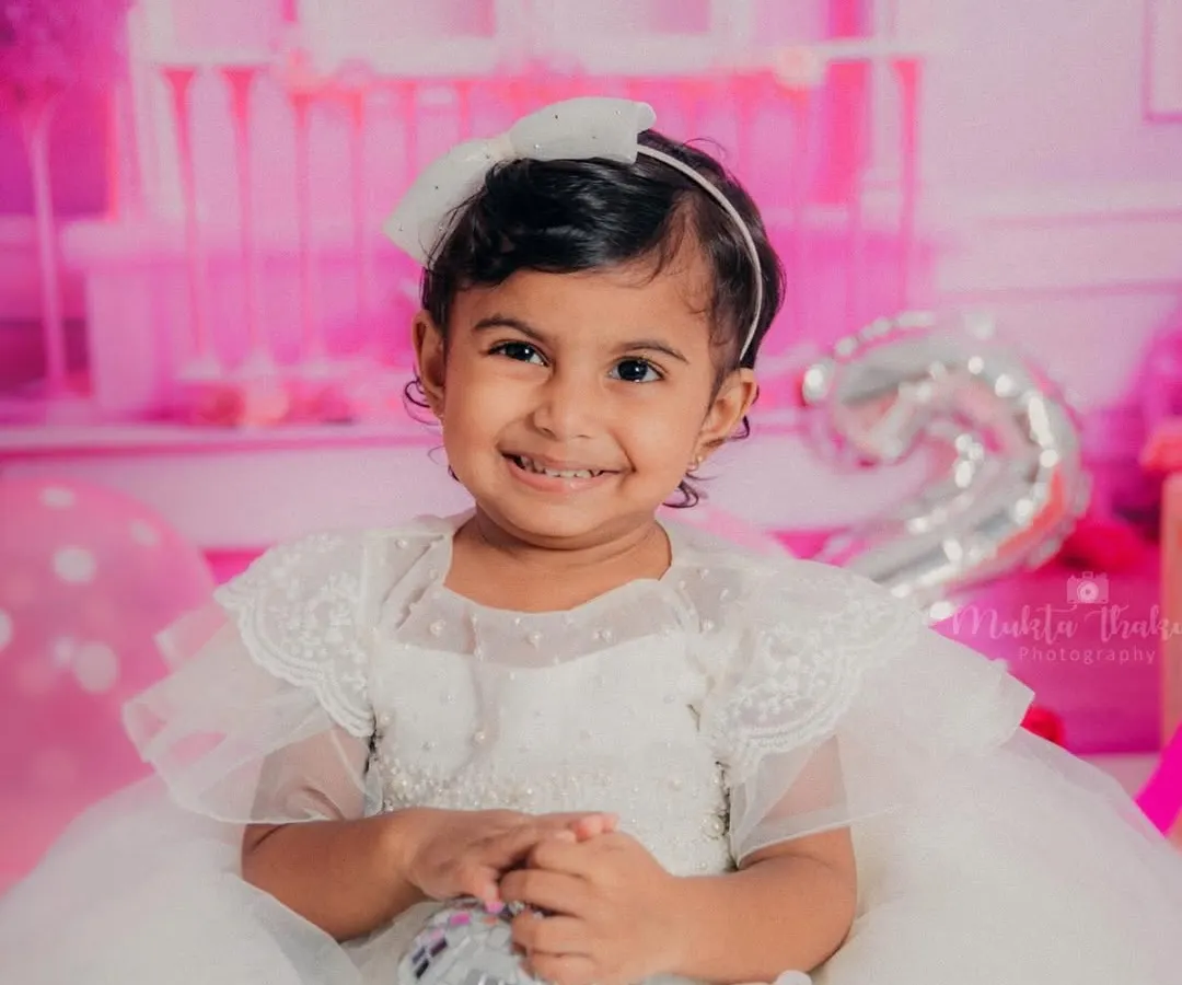 A dazzling smile from a two-year-old princess during her Barbie-themed birthday photoshoot. Her happiness truly lights up the entire studio.