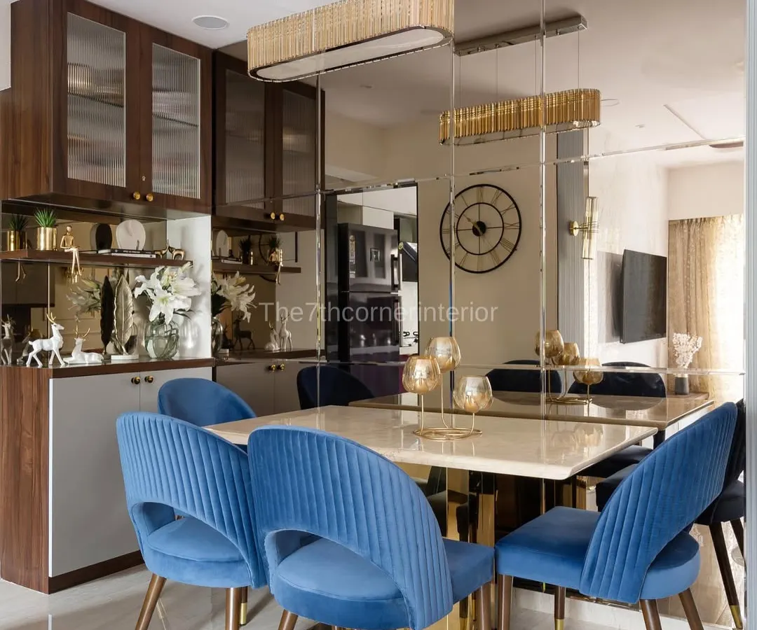 This dining space from 'The Adobe' project was designed to feel both grand and intimate. The deep blue upholstered chairs provide a rich pop of color against the Italian marble tabletop, while the mirrored wall cladding visually expands the space, creating an elegant setting for memorable meals.