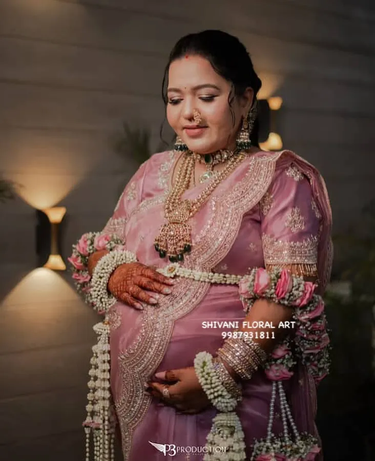 For this beautiful mom-to-be's baby shower, I created a full set of fresh flower jewellery. The look features a delicate floral shela, heavy kalire made from jasmine and rose, and matching armlets, all designed to complement her pink saree and make her feel special.