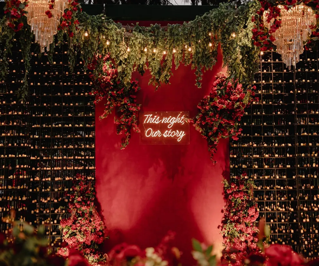 I believe in creating atmosphere that you can feel. For this sangeet, we painted the night in passionate reds, using a custom neon sign, a wall of candles, and untamed florals to build an immersive, electric energy for a night of celebration.