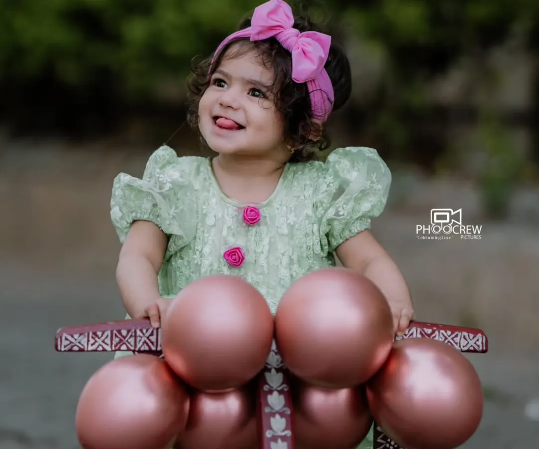 Capturing the pure, unfiltered joy of childhood is what we love most. This outdoor portrait for Bhoomija's first birthday shoot shows her delightful personality shining through as she plays with her little walker.