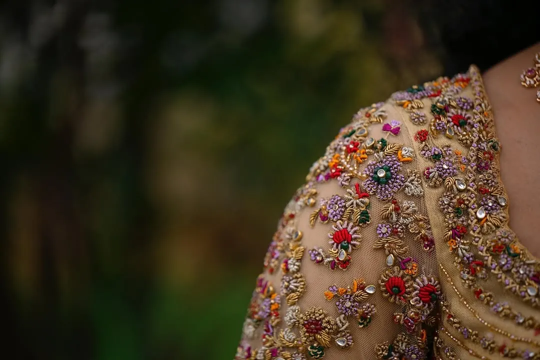 This is where the magic lies. A close up of a hand embroidered blouse sleeve, showcasing intricate, multi colored floral zardozi and beadwork on sheer fabric. Each stitch is a testament to the hours of artistry poured into my creations.