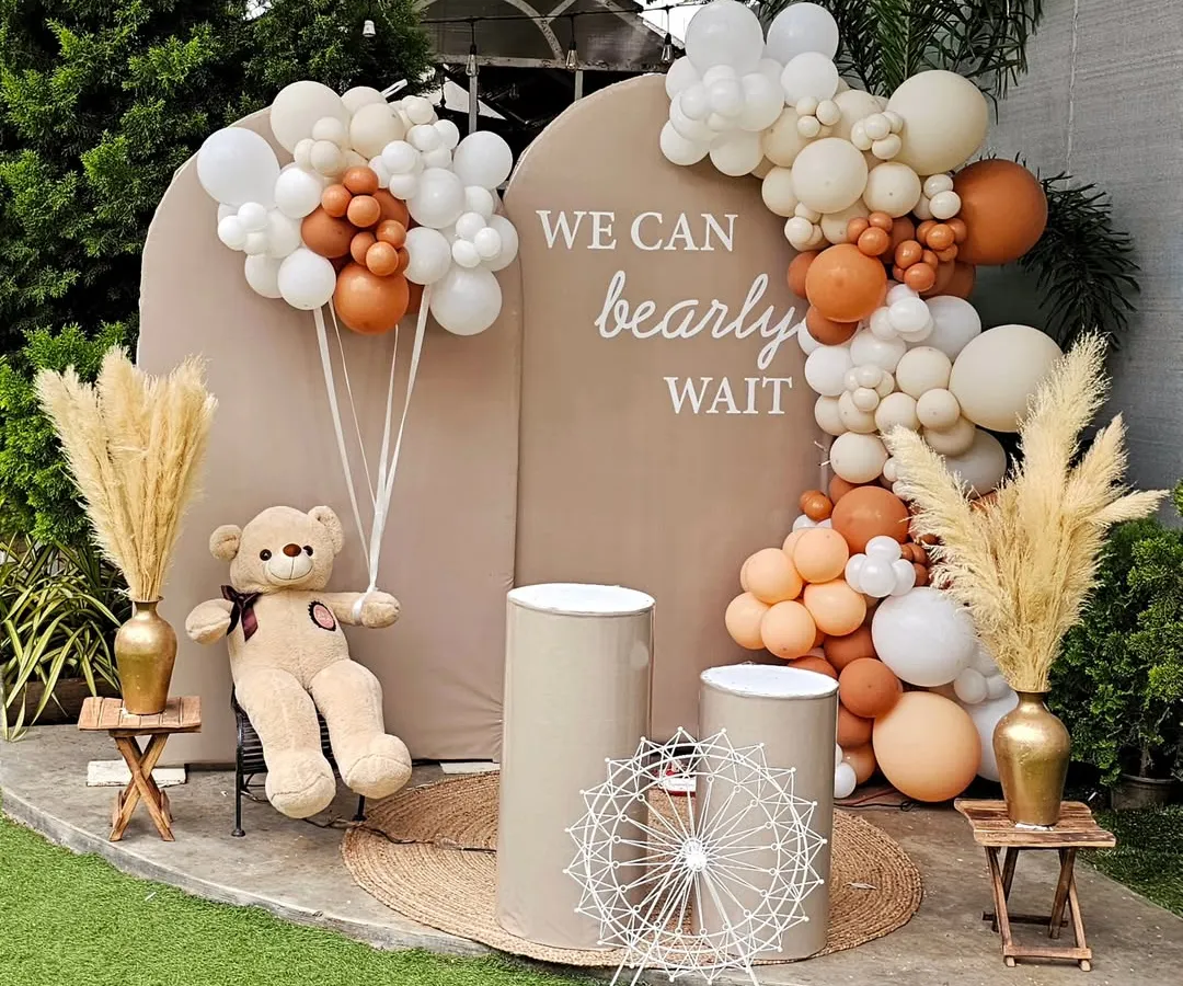 The "We can bearly wait" theme is perfect for a sweet and modern baby shower. This outdoor setup features a neutral color palette with beige, brown, and white balloons, pampas grass, and a cute teddy bear holding his own balloon bouquet.