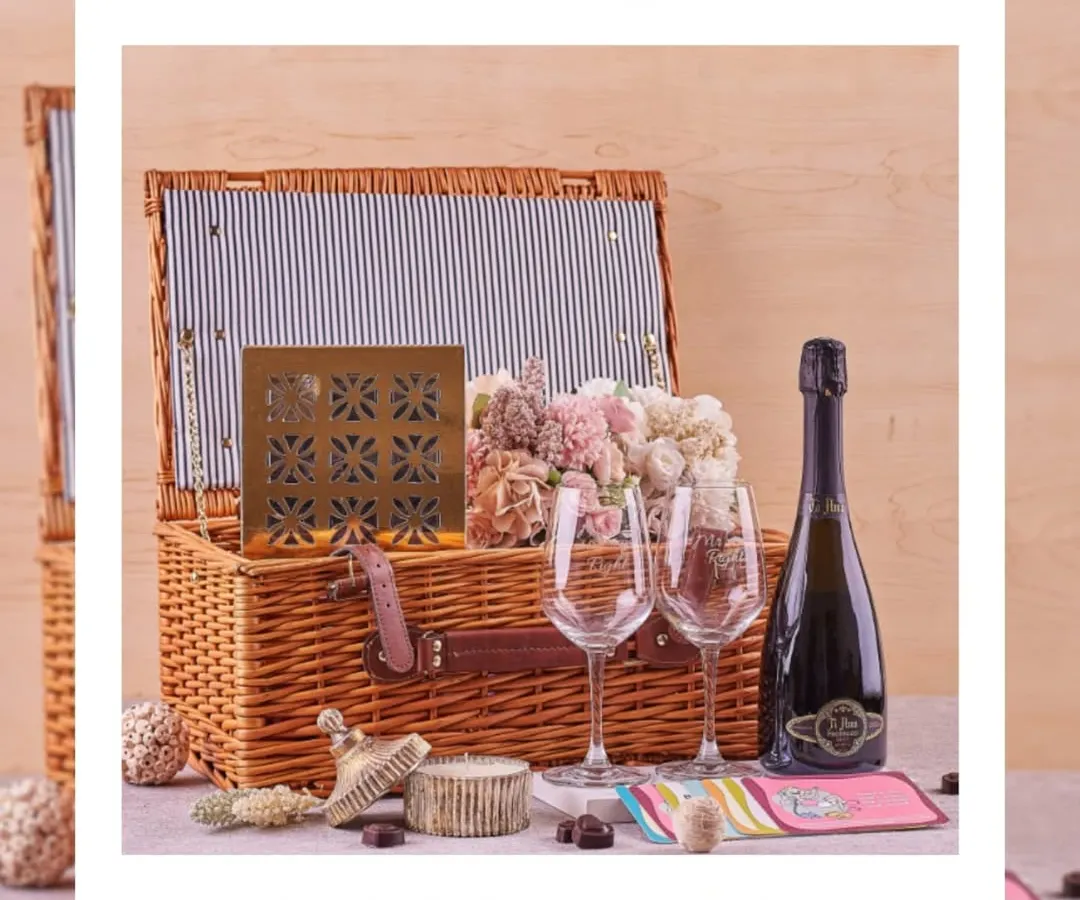I designed this elegant wedding hamper as the perfect romantic gesture for newlyweds. It includes a classic wicker picnic basket, sparkling wine, engraved glasses, and a selection of fine chocolates and flowers, setting the scene for a memorable celebration.