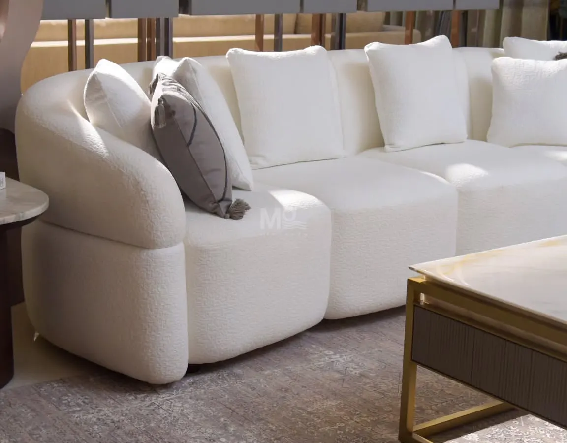 Introducing the Aether Sofa, where comfort flows in a gracefully curved silhouette. Draped in a high-quality ivory bouclé, its deep, generous cushions create a cocoon of pure comfort, offering a timeless centerpiece for a modern, serene living room.