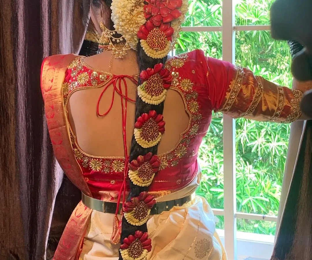 A South Indian bridal look is incomplete without the perfect hairstyle. This is a detailed view of a traditional Poola Jada, intricately woven with fresh flowers and classic hair jewels for a timeless and regal finish.
