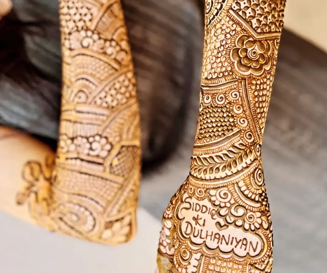 Your mehendi can include special phrases that are meaningful to you. Here, we incorporated "Siddi ki Dulhaniyan" directly into the detailed pattern on the back of the hand, making the bridal henna truly one of a kind.