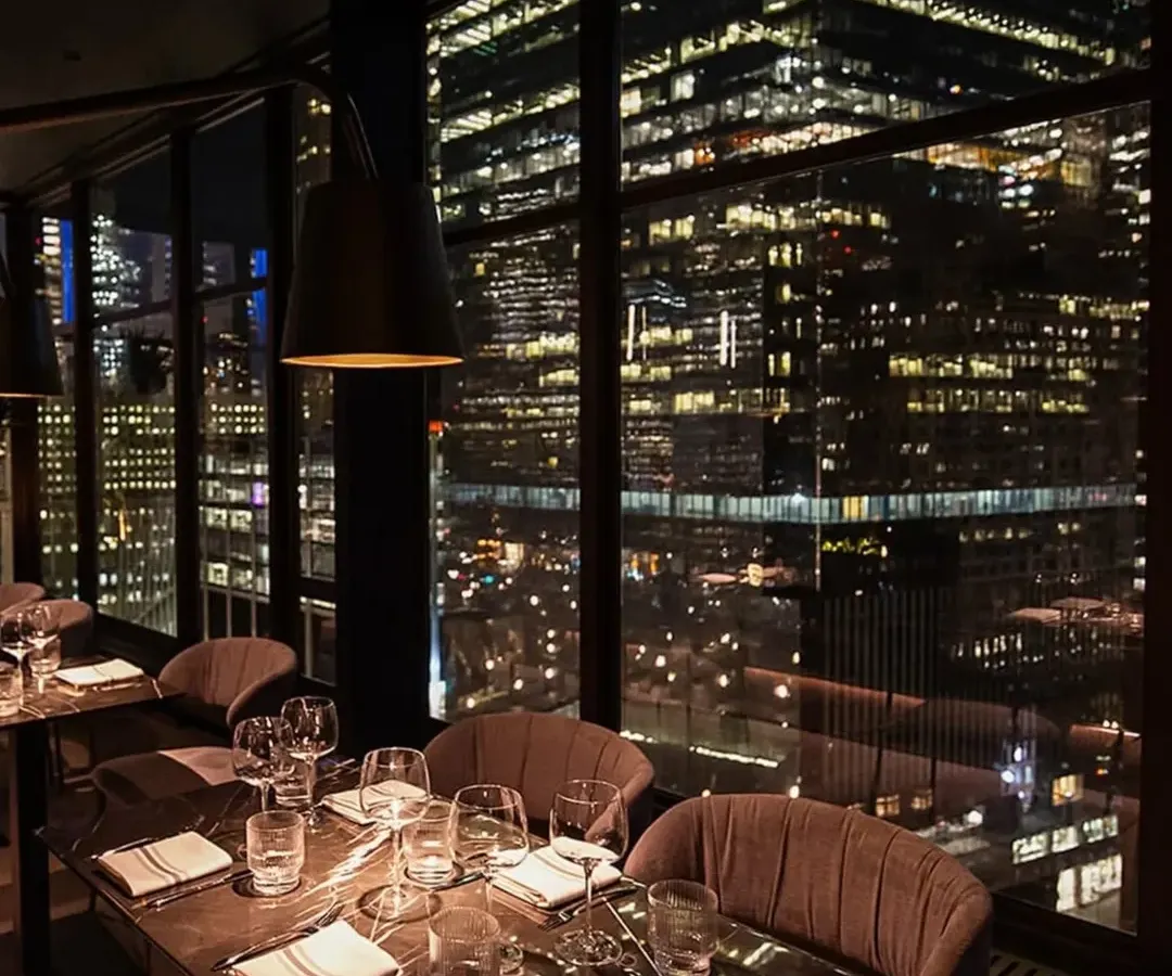 The magic of a New York City evening from our One40 Rooftop restaurant project. We designed this space to capture the city's energy, with floor-to-ceiling windows that frame the glittering skyline, creating an unforgettable dining atmosphere.