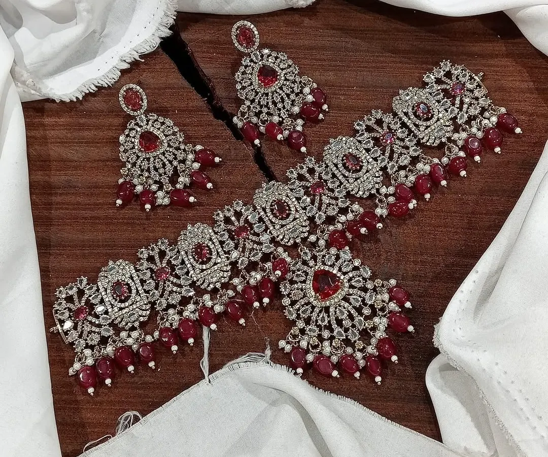 My premium Victorian choker sets are perfect for adding vintage elegance to your bridal or festive look. This particular set features intricate silver work studded with brilliant stones and rich red bead drops.