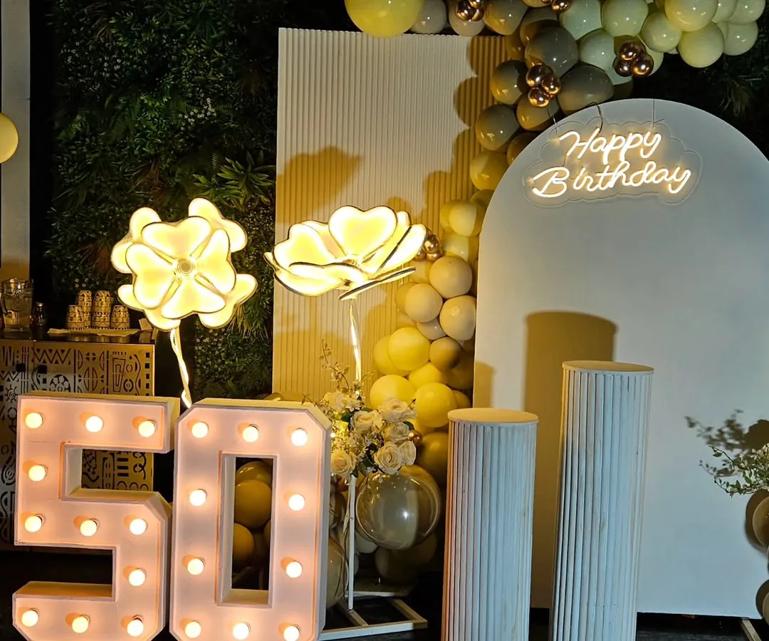 Celebrating a 50th birthday calls for something special and elegant. This setup features a classy white and gold theme with marquee numbers, a custom neon sign, and soft lighting to create a sophisticated atmosphere.