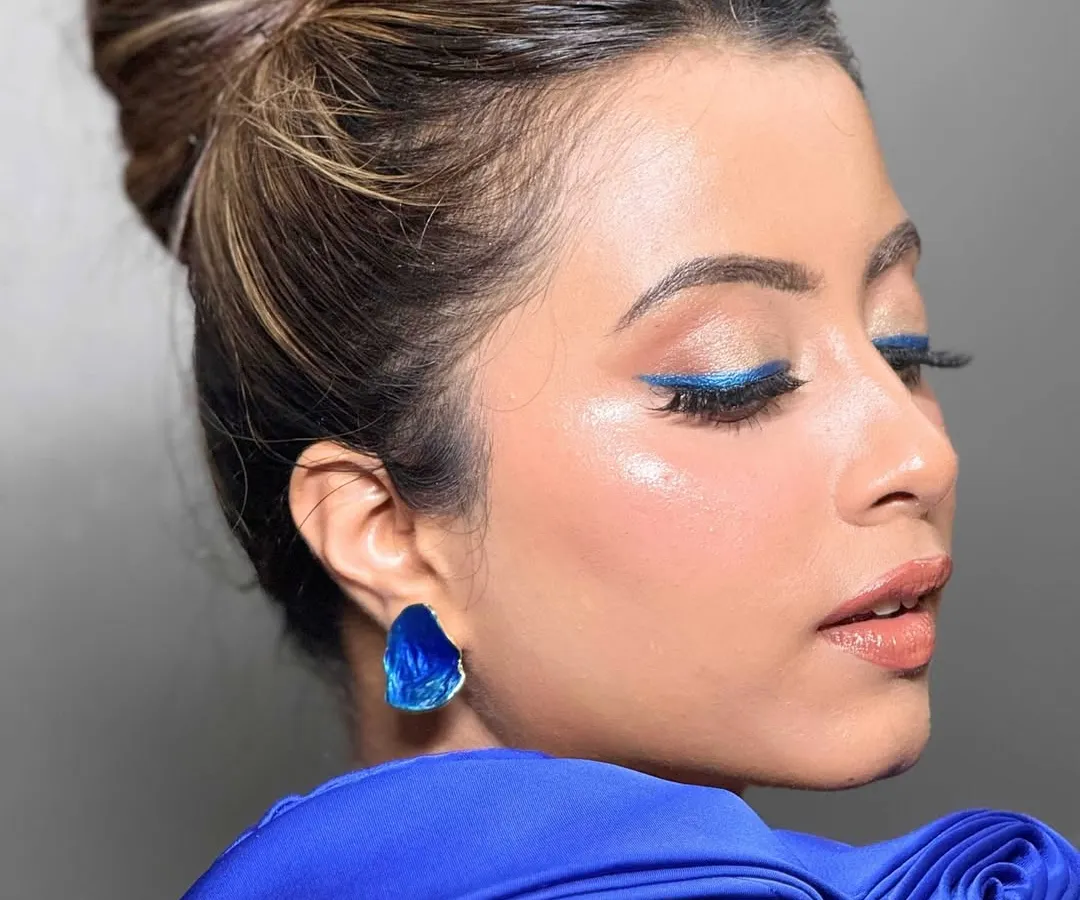 A pop of color can transform a whole look. For this modern party style, I used a sharp, electric blue winged liner to create a statement eye, balanced with glowing skin and a neat top knot for a chic and unforgettable finish.