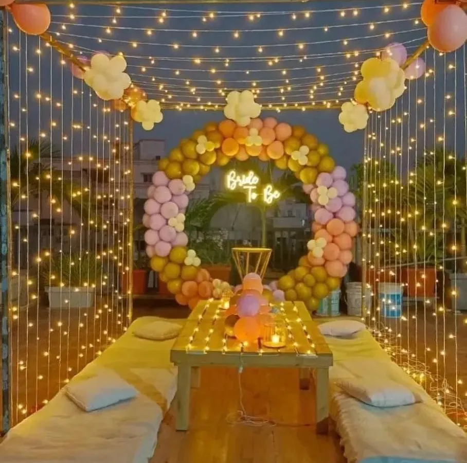 Transforming a simple rooftop into a dreamy 'Bride to Be' celebration space. This setup features a canopy of fairy lights, a custom balloon ring, and comfortable floor seating, creating a magical and intimate atmosphere perfect for a bridal shower under the stars.