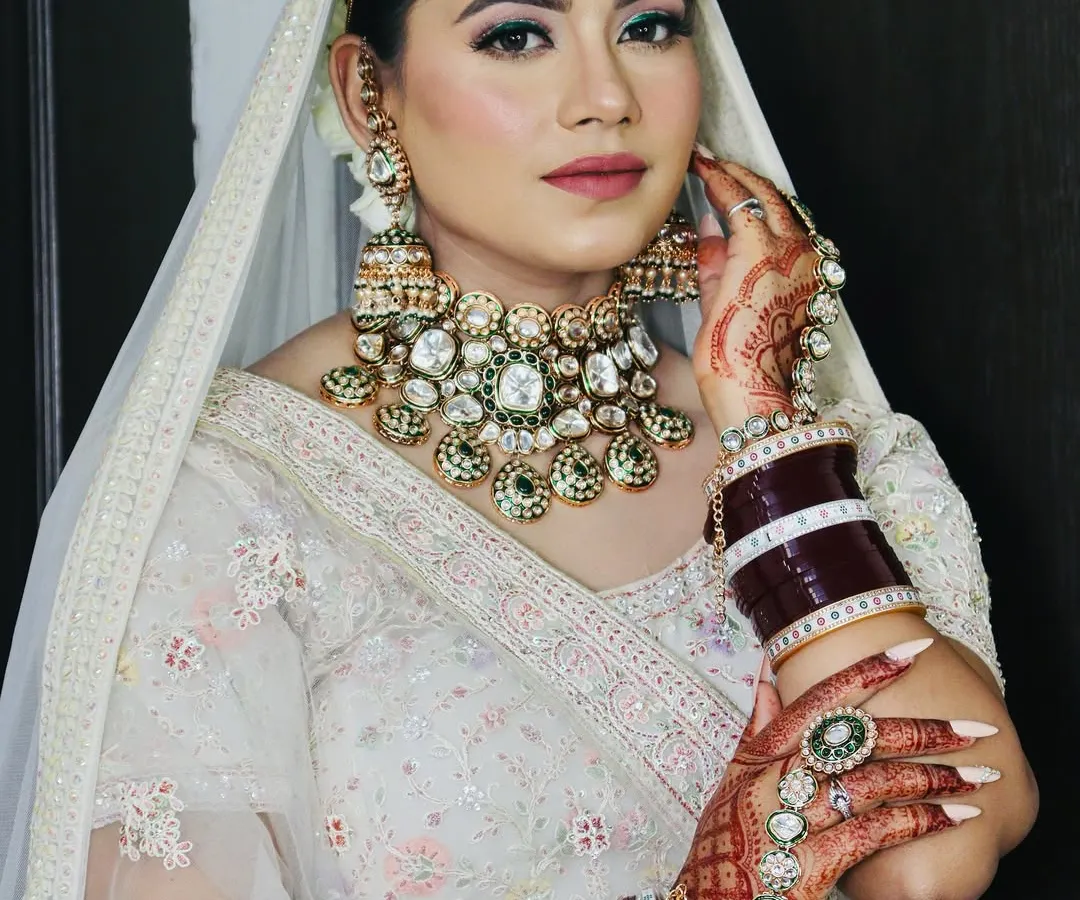 For this bride, we chose a contemporary yet timeless look with a stunning white lehenga. I focused on a dewy skin finish, soft pink eyeshadow with a hint of shimmer, and elegant Kundan jewelry to complete the Anand Karaj bridal style.